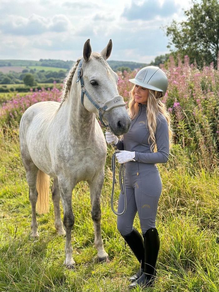 Rider in the grey My Lady set standing with a grey horse in a meadow