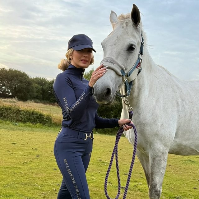 Rider in the navy My Lady set with a white horse in the paddock